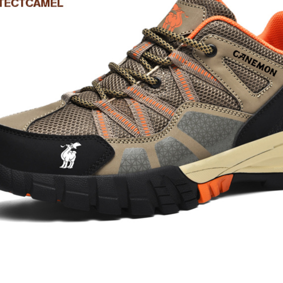 Close up of tan mesh and microfiber shoe with orange laces, camel logo on black toe cap and deep lugged sole