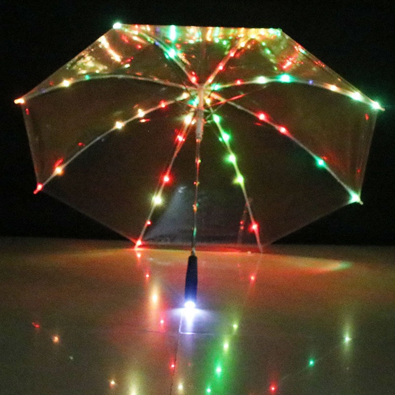 Front view of a clear LED umbrella at night with multicolor LED dots along every rib and a lit handle tip