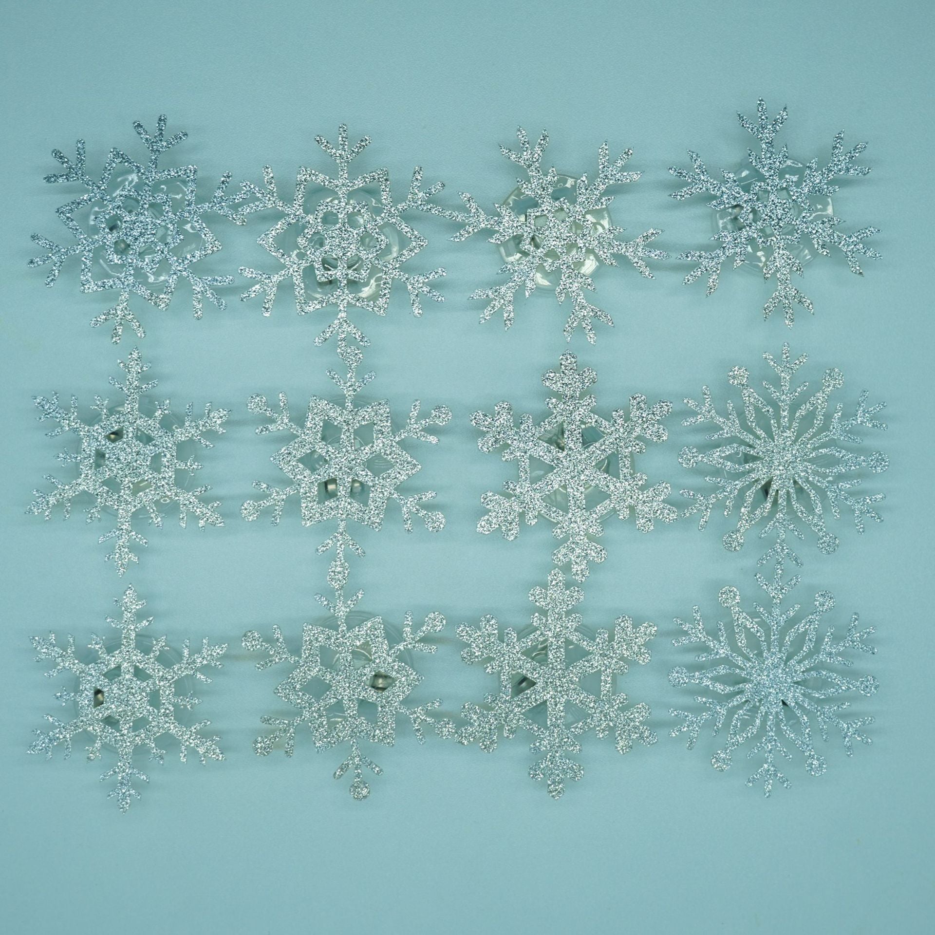 Silver glitter snowflake decals on a light blue background showing their see through centers