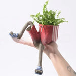 Resin lower body planter in red striped shorts and blue sandals holding a fern