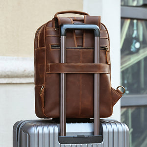 Back of the leather backpack with a strap sleeve sliding over a rolling suitcase handle