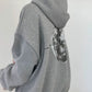 Light gray oversized hooded sweatshirt seen from the side and back with a large grayscale moon print