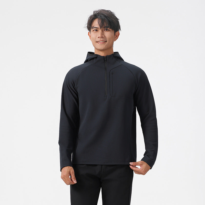 Man in a black half zip hooded sweatshirt with a zipped chest pocket, hands lowered, front view for size M