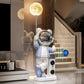 Blue and white astronaut bear statue with moon lamp and Bluetooth symbol beside a staircase