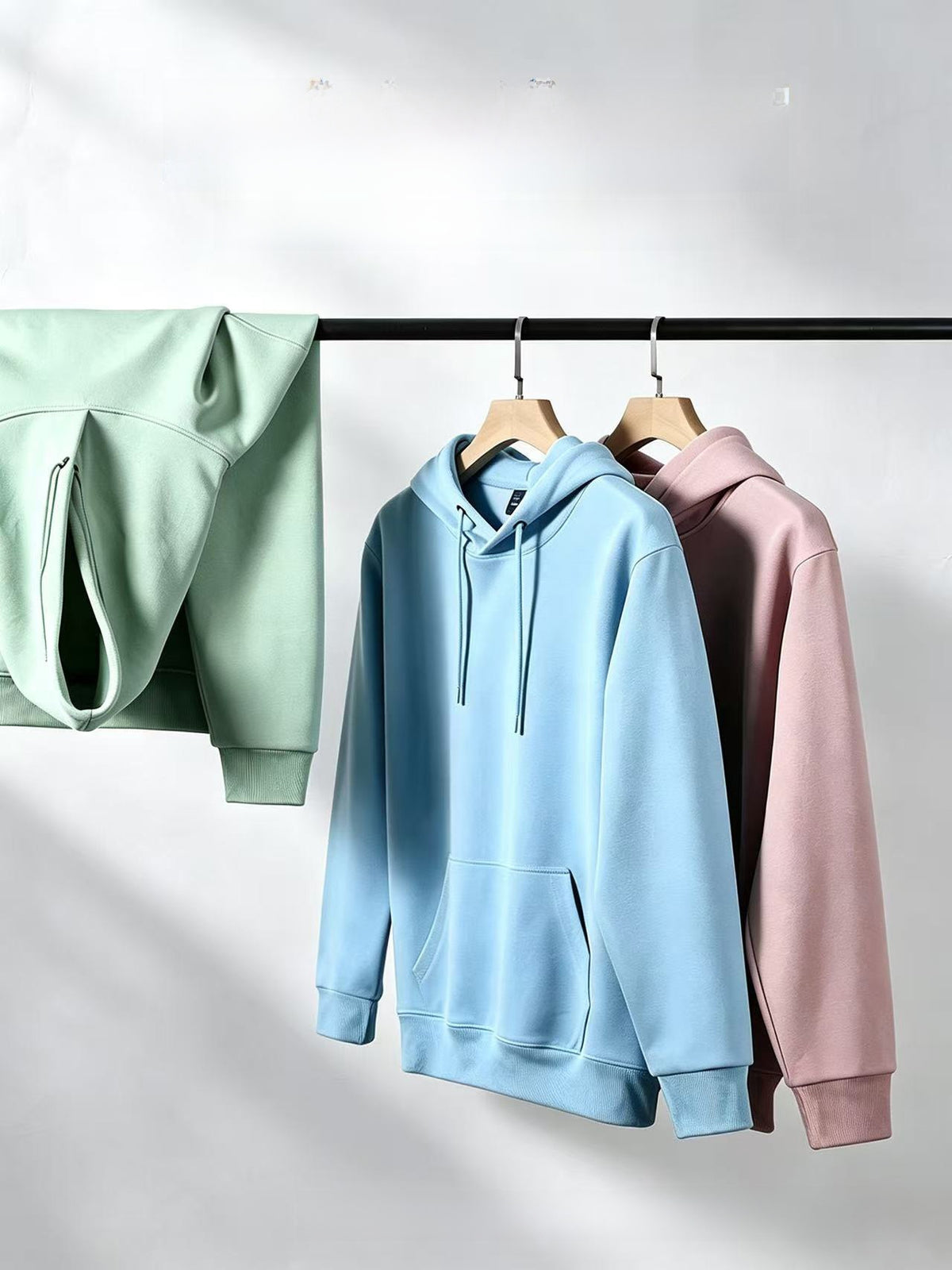 Light blue, mint and mauve hoodies hanging on a clothes rail, colors not among the available options