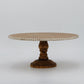 Round beaded rim wooden cake stand with turned walnut pedestal on a grey background
