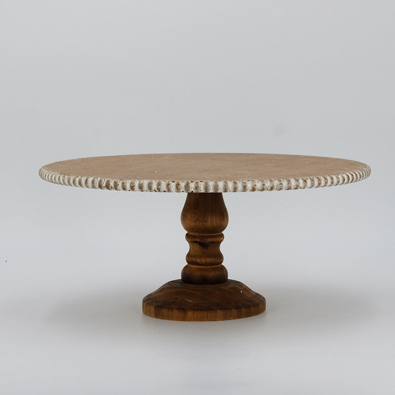 Round beaded rim wooden cake stand with turned walnut pedestal on a grey background