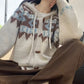 Fair Isle knit cardigan with drawcord hood and horn-shaped buttons, hand resting on the knee