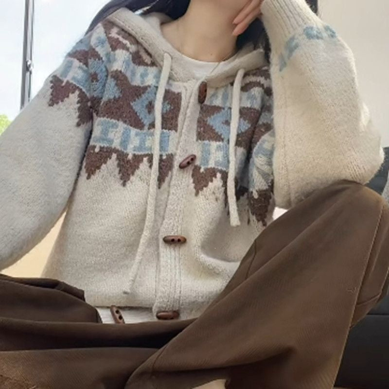 Fair Isle knit cardigan with drawcord hood and horn-shaped buttons, hand resting on the knee