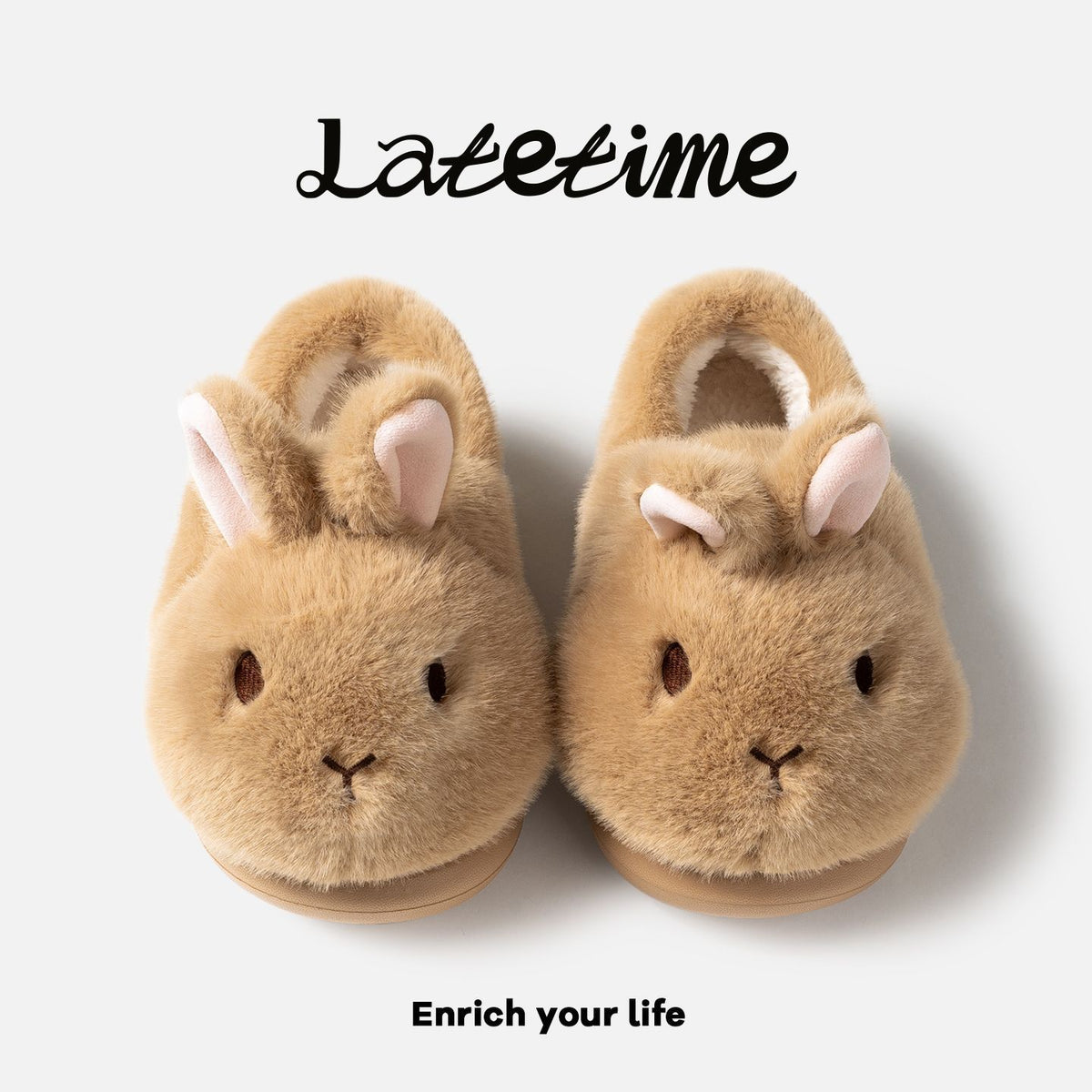 Pair of brown bunny plush slippers seen from above on a light panel with script lettering and a slogan, view 3 of 5