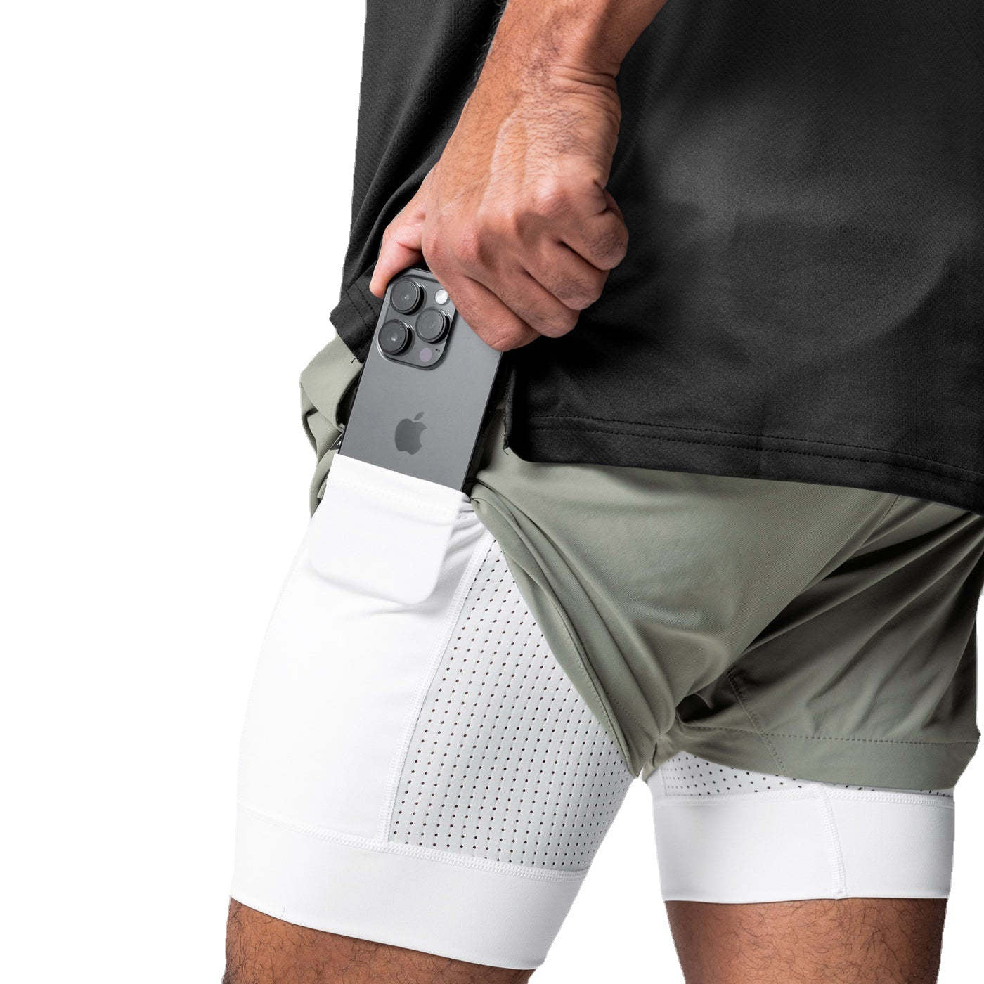 Man wearing the two in one training shorts in sage green, with a phone held in the white liner side pocket