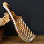 Marbled amber and cream plastic hair comb resting on a wooden stand against a dark backdrop