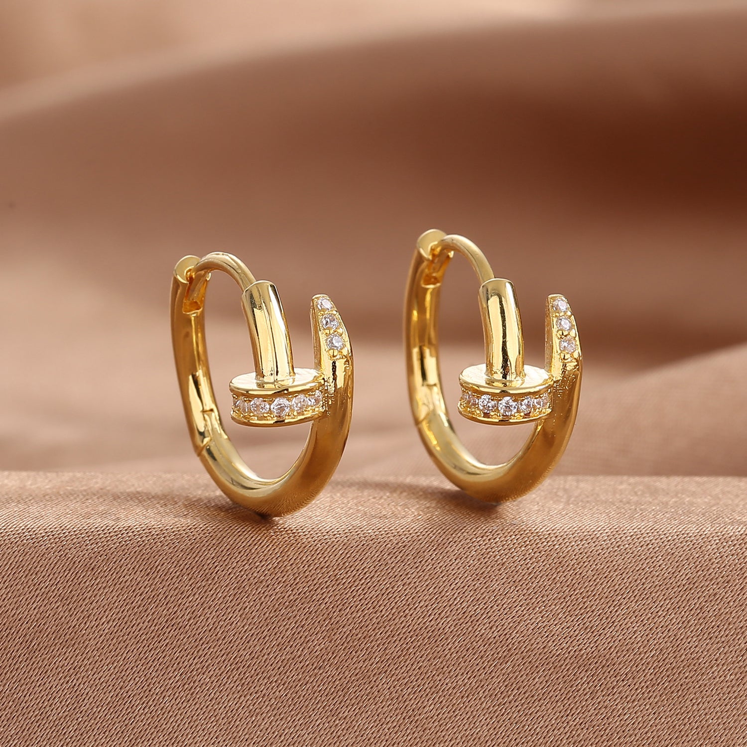 Gold zirconium nail stud earring held in hand to show its small scale