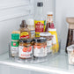 Clear oval rotating tray on a refrigerator shelf holding sauce jars, soy sauce and condiment bottles