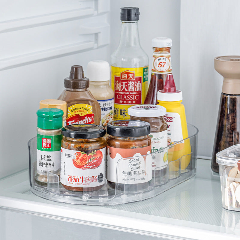 Clear oval rotating tray on a refrigerator shelf holding sauce jars, soy sauce and condiment bottles
