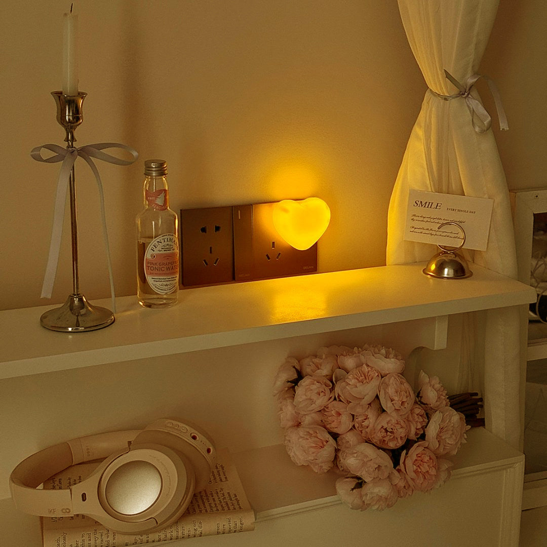 Warm amber heart night light glowing in a softly lit bedroom corner