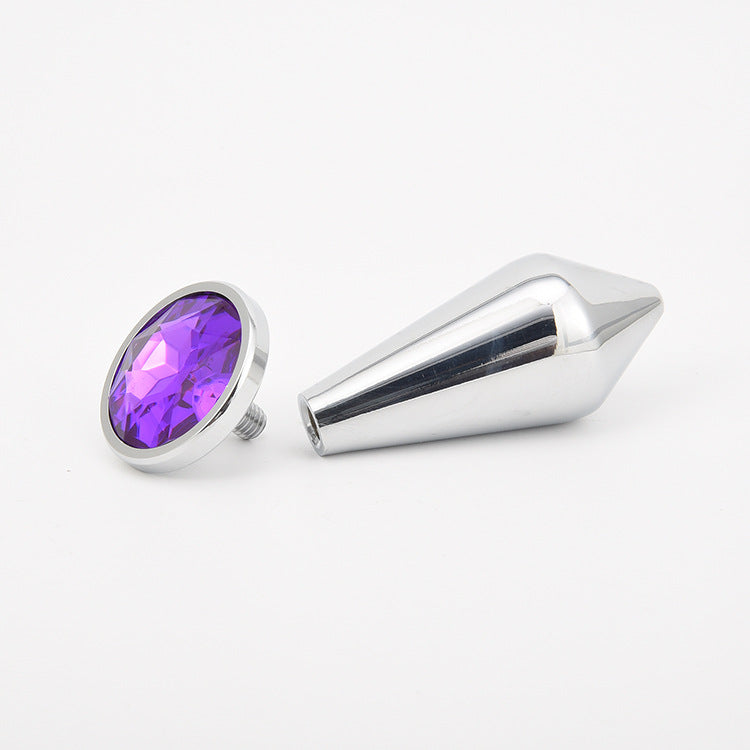 Detachable metal anal plug shown on a styled surface in its polished finish