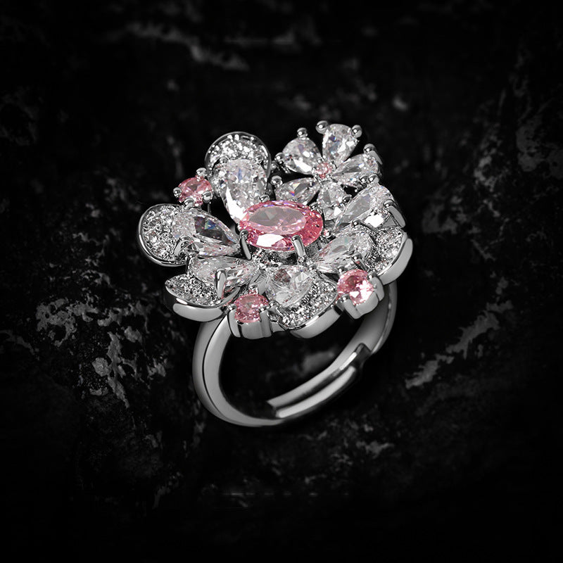 Floral cluster ring mixing pink and clear simulated stones into petal shapes, dark stone background