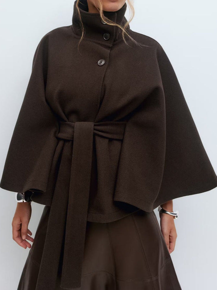 Black belted cape jacket with a stand collar, offset buttons and wide draping cape sleeves