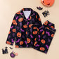 Dark pajama set with orange pumpkins and purple bats laid flat with Halloween props