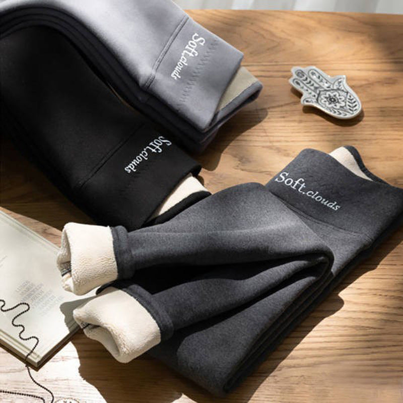 Black and dark gray fleece lined leggings folded on a wooden table with the cream lining showing