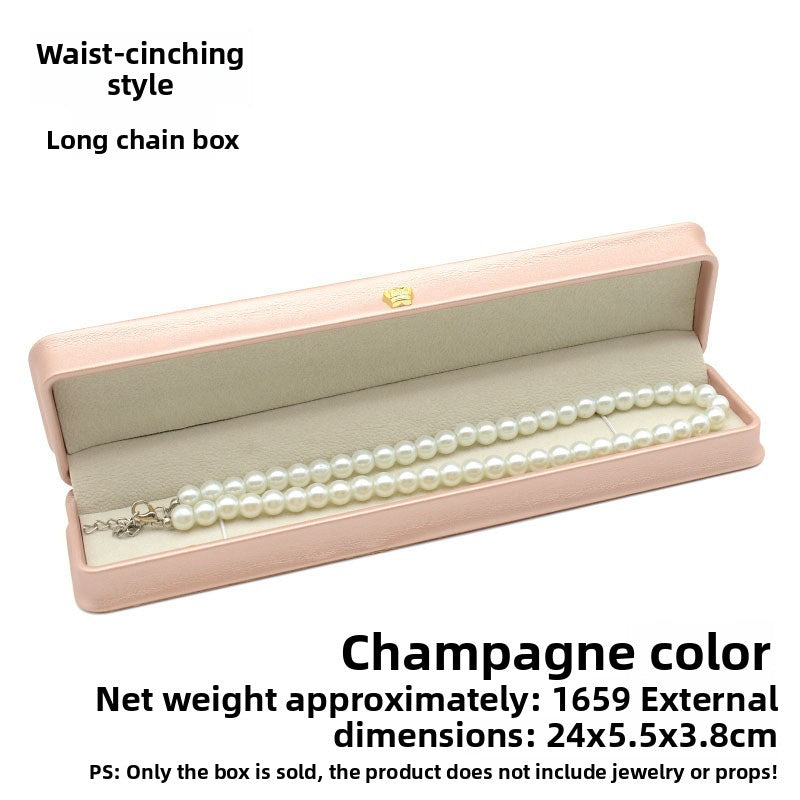 Open champagne pink crown clasp necklace box with a pearl necklace on the grey lining
