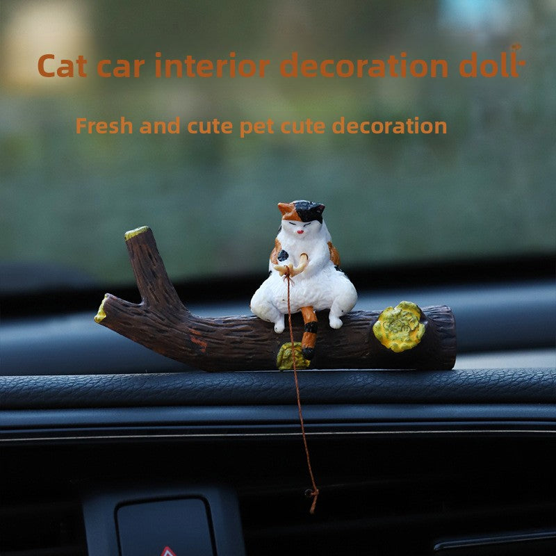 Calico cat figurine fishing from the resin branch set on a car dashboard