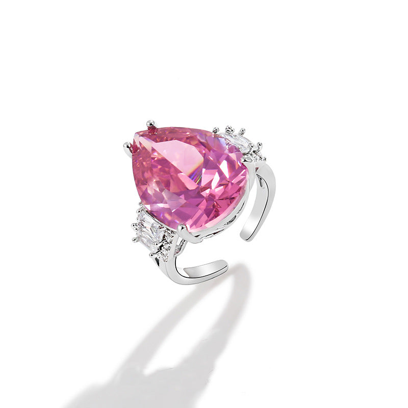 Wide pear cut pink stone with clear baguette accents on an open adjustable band, white background