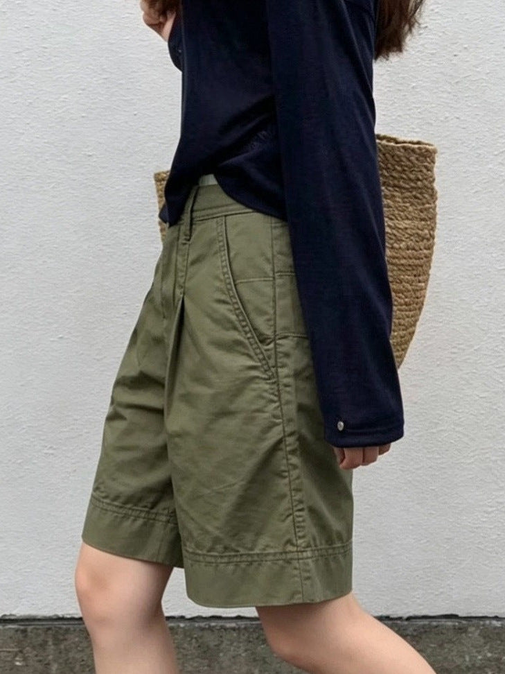 Walking side view of knee-length olive green Bermuda shorts with deep cuffed hem