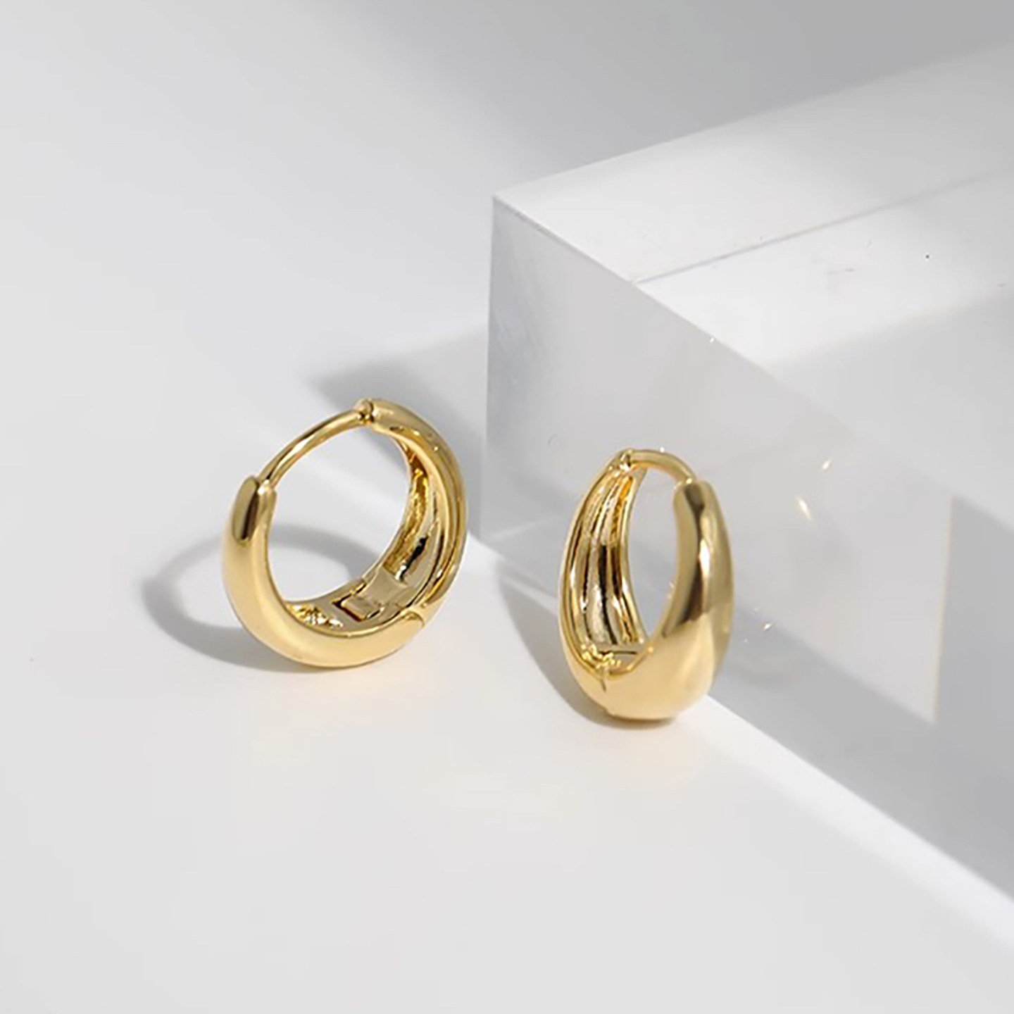 Hoops worn in the lobe of a model with hair tucked behind the ear