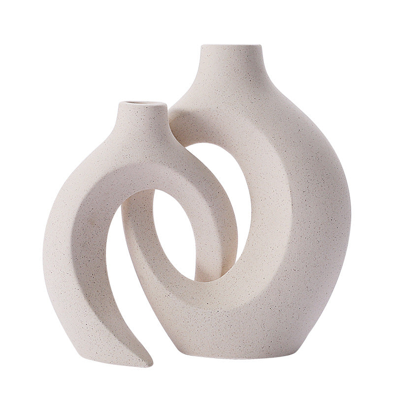 Curved hollow ceramic vase holding dried stems on a console