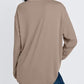 Back view of a khaki long sleeve rayon top with a rounded hem worn with blue jeans