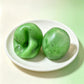 Kiwi pour of the fruit smoothie squishy, two green balls on a white dish, one pressed in
