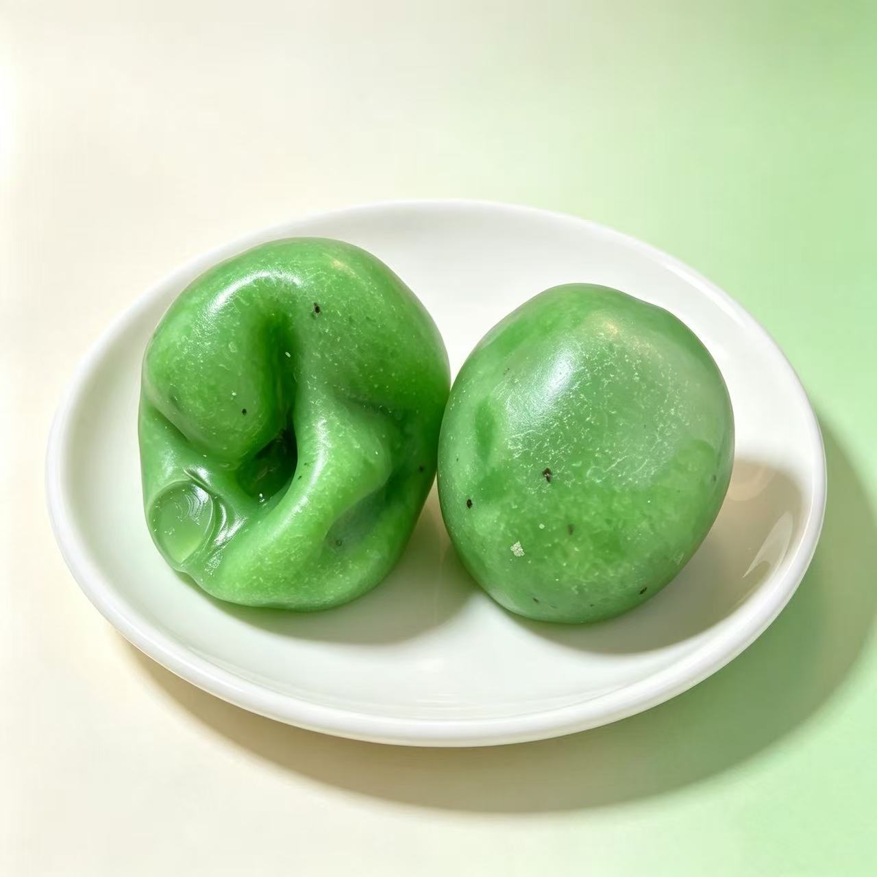 Kiwi pour of the fruit smoothie squishy, two green balls on a white dish, one pressed in