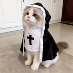 Ragdoll cat wearing a black and white hooded nun costume with a black cross, sitting on a tiled floor