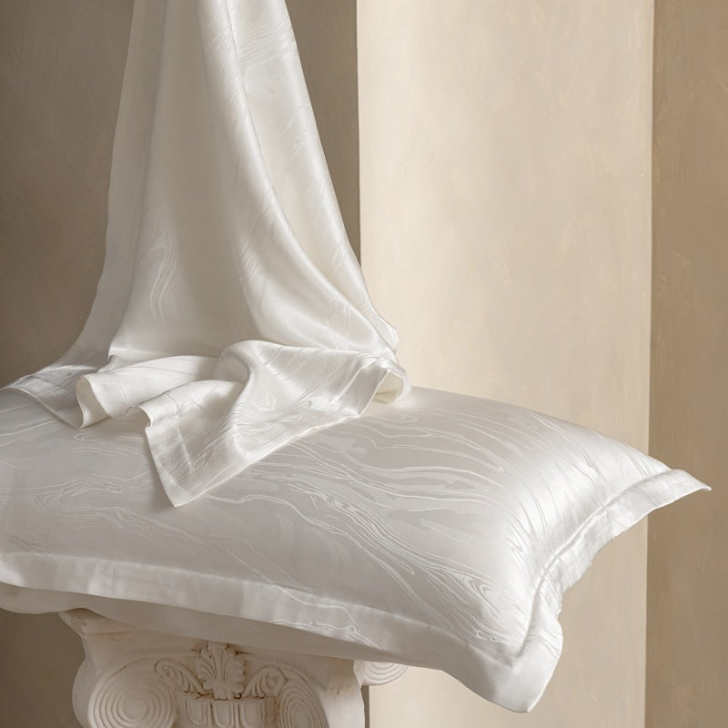 Ivory Wave jacquard silk pillowcase with white silk draped over it, pair option