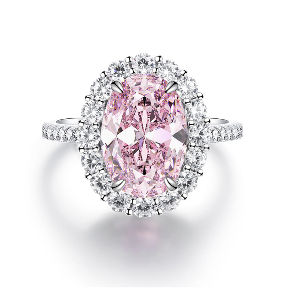 Top view of the pink oval stone ring, four prongs holding the centre inside a ring of clear stones