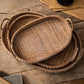 Three nested oval trays seen from above, showing the woven rattan base and the studded wooden rim