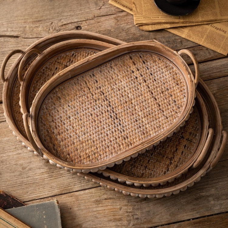Three nested oval trays seen from above, showing the woven rattan base and the studded wooden rim