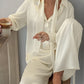 Buttercream loose shirt and wide leg trousers set worn seated on a wooden stool with a coffee