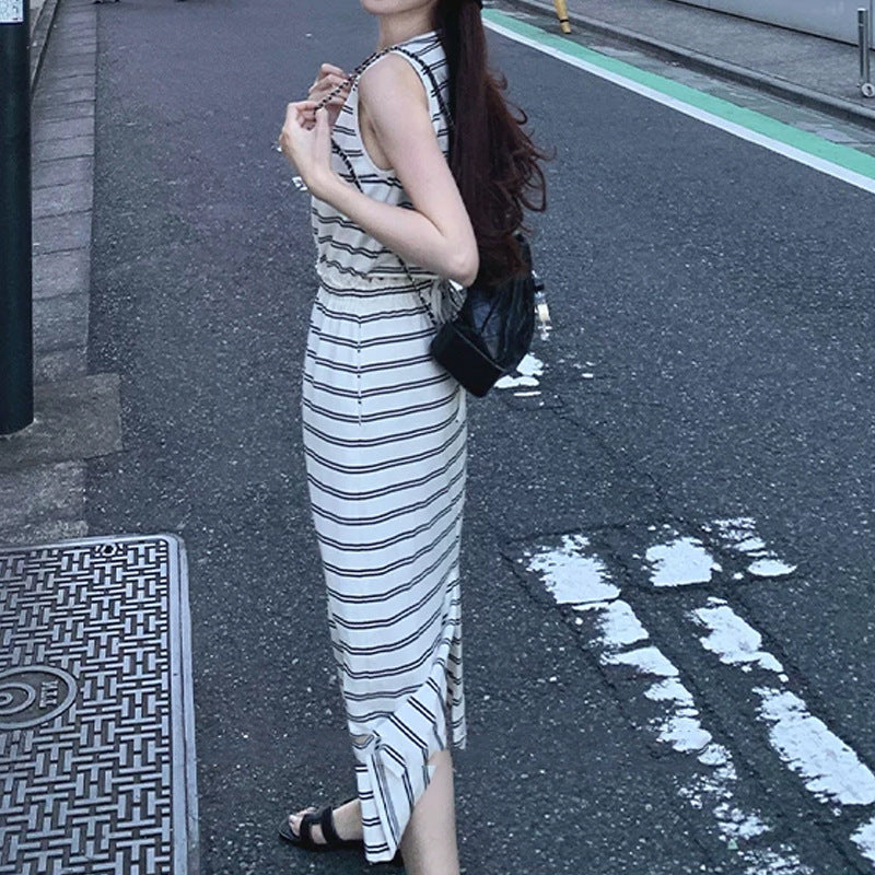 Side profile of striped sleeveless maxi dress with hem slit and slim ankle-length skirt