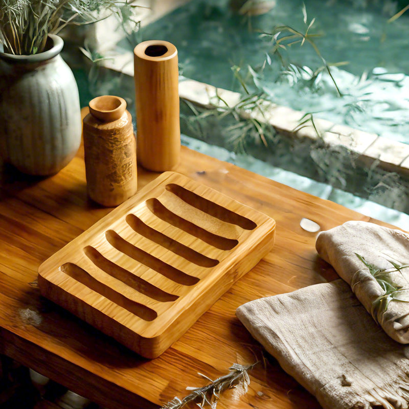 Slatted bamboo soap dish on a wooden shelf with ceramic vases and linen towels