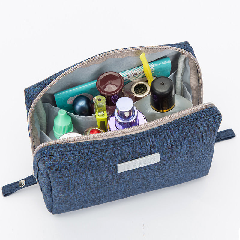 Cube travel toiletry bag in navy coated Oxford cloth open to show toiletries inside