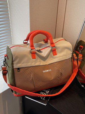 Beige and brown colorblock travel duffel with orange handles and trim on a white suitcase