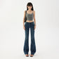 Model in low rise dark wash flared jeans, front view with a bag showing the long flared leg line