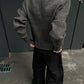 Back view of the gray ribbed knit cardigan on a man with hands in the trouser pockets, squared shoulders