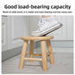 Light rubberwood round stool with tapered legs and low stretcher ring on wood floor