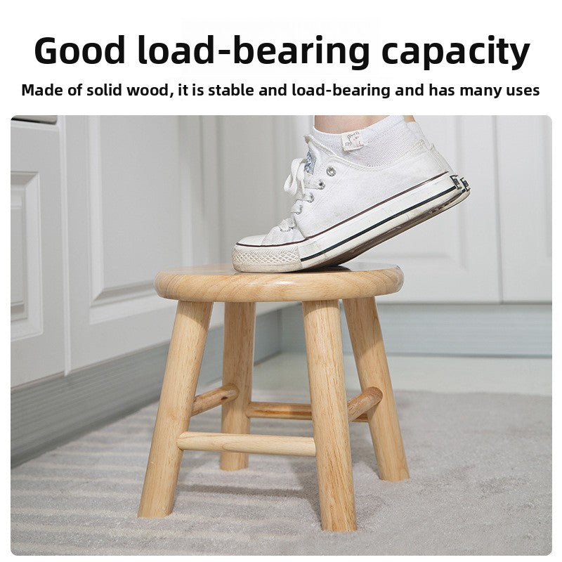 Light rubberwood round stool with tapered legs and low stretcher ring on wood floor
