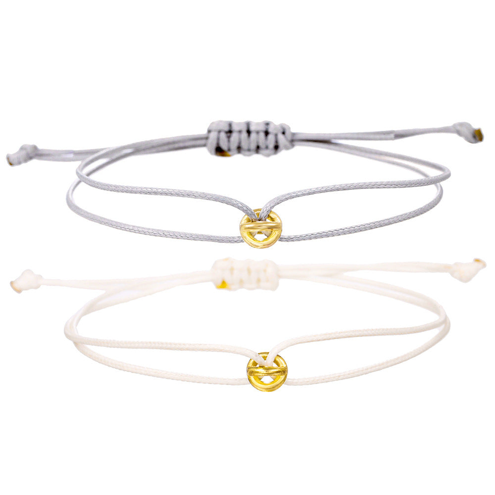 Gray and cream cord bracelets with gold tone charms laid flat as a matching pair