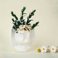White ceramic cowboy hat vase with white blooms and greenery on a beige background